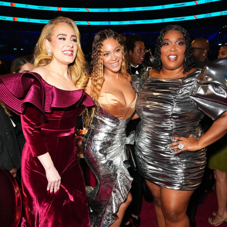 Stylisches Superstar-Trio: Den voluminösen Red-Carpet-Look in Orange hat Lizzo für ihren Auftritt bei den Grammys dann noch mal gegen ein gerafftes Minikleid in Silber ausgetauscht, in dem sie gemeinsam mit Adele und Beyoncé posiert.
