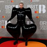 Okay! Sam Smith besucht die Brit Awards in einer Konstruktion aus Lackleder. Die Schultern sowie die Oberschenkel sind pointiert herausgearbeitet.
