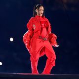 Sie macht Rot zu ihrer Farbe: Sängerin Rihanna trägt für ein Medley ihrer besten Hits zur Halbzeitshow des Super Bowls einen Einteiler von Loewe, worüber sich das passende Bustier verbirgt. Der Gürtel, der leicht über ihrer Hüfte sitzt, verdeutlicht ihre freudigen Neuigkeiten noch einmal stärker: Rihanna erwartet ihr zweites Baby. Aber auch die kurze Daunenjacke von Alaïa verleiht ihren Baby-News den richtigen Rahmen. Motto: Freie Sicht auf den Bauch! Doch ...