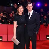 Schwarz ist immer eine gute Wahl, denken sich Alexandra Maria Lara und Ehemann Sam Riley. Mit funkelnden Glitzer-Bahnen erhält das T-Shirt-Kleid von Ralph Lauren der Schauspielerin einen Hauch von Brillanz. Nicht weniger auffällig präsentiert sich Sam Riley in Prada. 