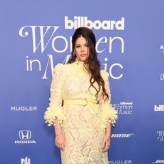 Lana Del Rey trägt einen – für sie typischen – Retro-Look auf dem blauen Teppich der Billboard Women in Music Awards. Das semi-transparente gelbe Kleid mit Blumen-Applikationen gibt den Blick auf ihre Unterwäsche in der selben Farbe frei. Die Schuhe sind nicht das einzig Goldene, was die Sängerin im Laufe des Abends trägt, ihr wurde der goldene Visionary Award überreicht. 