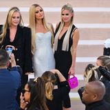 Bei Kathy, Paris und Nicky Hilton ist die Fashion-Show von Versace Familiensache. Gemeinsam posieren sie für die Fotograf:innen.