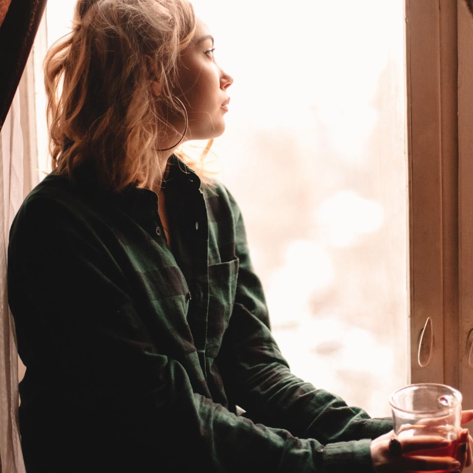 Frau schaut traurig aus dem Fenster: 4 toxische Denkmuster, die wir uns abgewöhnen sollten