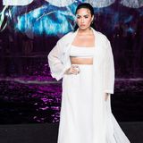 In einem strahlend weißen Look mit XL-Mantel besucht Demi Lovato die Modenschau in Miami.   