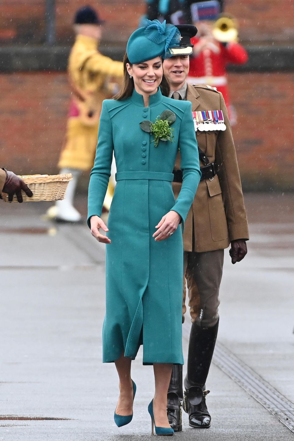 Bei der jährlichen Parade zum St. Patrick's Day in Aldershot begeistert Kate in einem schicken blaugrünen Mantelkleid von Catherine Walker und führt damit eine jahrelange Tradition fort. Seit ihrem ersten Auftritt beim irischen Nationalfeiertag setzt die Princess of Wales auf Mantelkleider in Grün. Dennoch ist dieser Auftritt eine Premiere, denn Kate ist neuerdings Colonel des 1. Bataillons der Irish Guards. Sie ehrt den irischen Nationalpatron "St. Patrick" mit riesengroßem Kleeblattanstecker. 