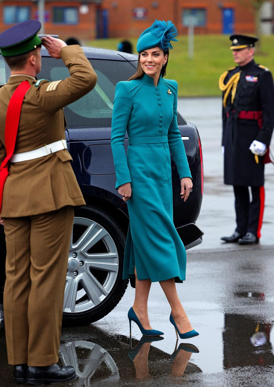 Im türkisfarbenen Mantelkleid von Catherine Walker strahlt Kate den Regen in Aldershot einfach weg. 
