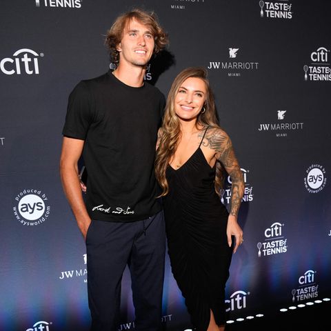 Auf dem blauen Teppich der "Citi Taste of Tennis" in Miami funkeln Alexander Zverev und Sophia Thomalla, was das Zeug hält. In ihren Outfits verschmelzen sie fast gänzlich mit der Kulisse: In schwarzem Spaghettiträger-Kleid mit V-Ausschnitt präsentiert die Moderatorin nicht nur ihre Kurven, sondern auch ihre Tattoos. Der Tennisstar setzt auf klassische Casual-Eleganz aus Shirt, Anzughose und Sneakern von Adidas.