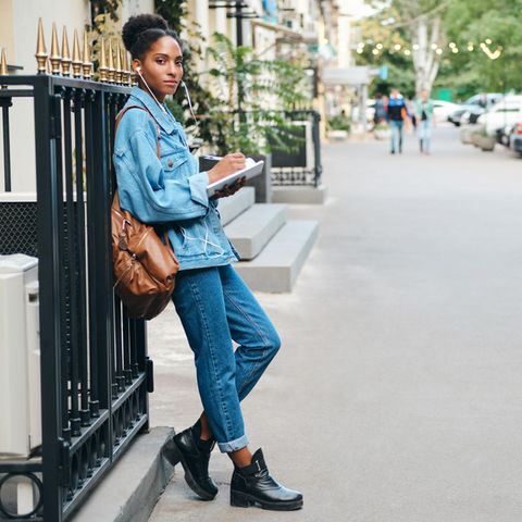Double Denim: Frau im Jeans-Look lehnt an einem Zaun