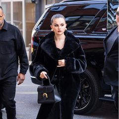 Warm eingekuschelt und trotzdem super elegant tritt Selena Gomez auf die Straßen New Yorks. Anlässlich eines Rare Beauty Events wählt die Sängerin einen langen schwarzen Faux-Fur-Mantel, eine Seidenbluse sowie eine schwarze Marlene-Hose. Große Ohrstecker und eine Tasche von Delvaux komplettieren den exquisiten Street Style.