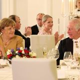 Nach einer herzlichen Rede, die König Charles größtenteils auf deutsch hält, nimmt der britische Royal neben Angela Merkel Platz. 