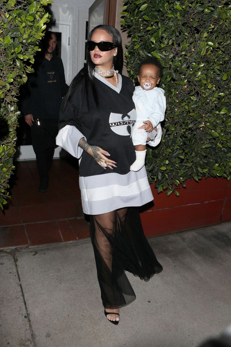 Wo Rihanna ist, ist Blitzlichtgewitter sicher! Beim Abendessen mit ihrem Sohn zeigt sich die Sängerin im oversized Wu-Tang-Jersey und fetter Diamantkette. XL-Sonnenbrille und ein transparenter Rock runden den Look ab und beweisen, dass Rihanna auch in ihrer zweiten Schwangerschaft modisch Vollgas gibt.