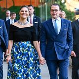 Schöner als der blumige Ballonrock in Blau mit schulterfreiem, eleganten Top ist nur Victorias breites Lächeln. Mit Ehemann Daniel, in farblich stimmigem Anzug, an der Hand besucht sie ein Dinner in Sydney.