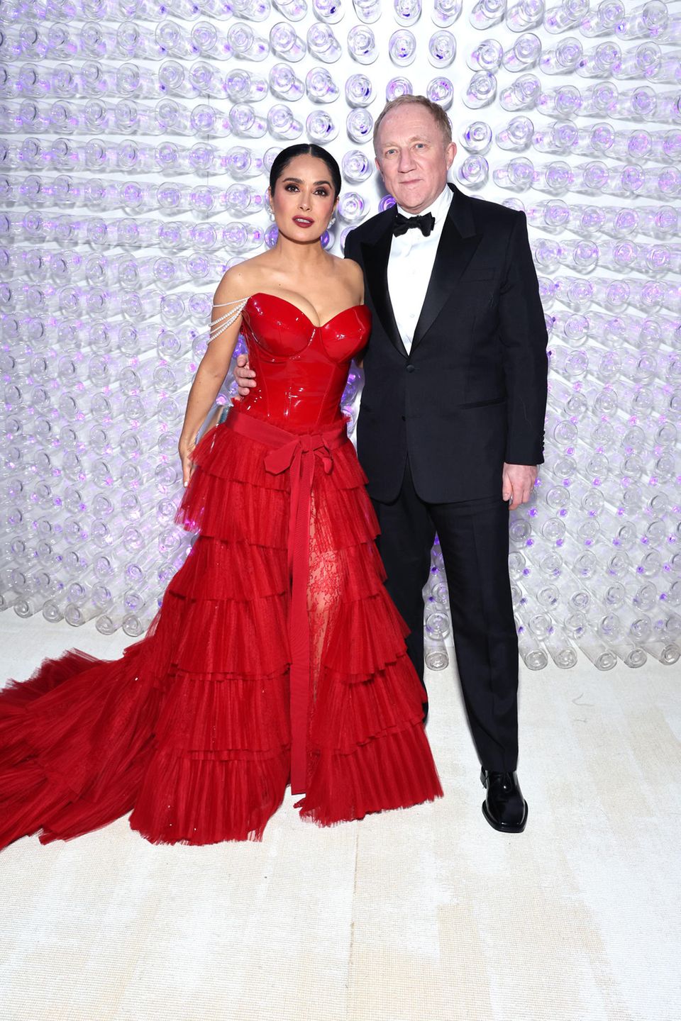 Bras dessus bras dessous, Salma Hayek et son mari François-Henri Pinault assistent au Met Gala.  Selma porte une robe rouge avec corsage en dentelle et vinyle de Gucci.  François apparaît dans un costume très classique.