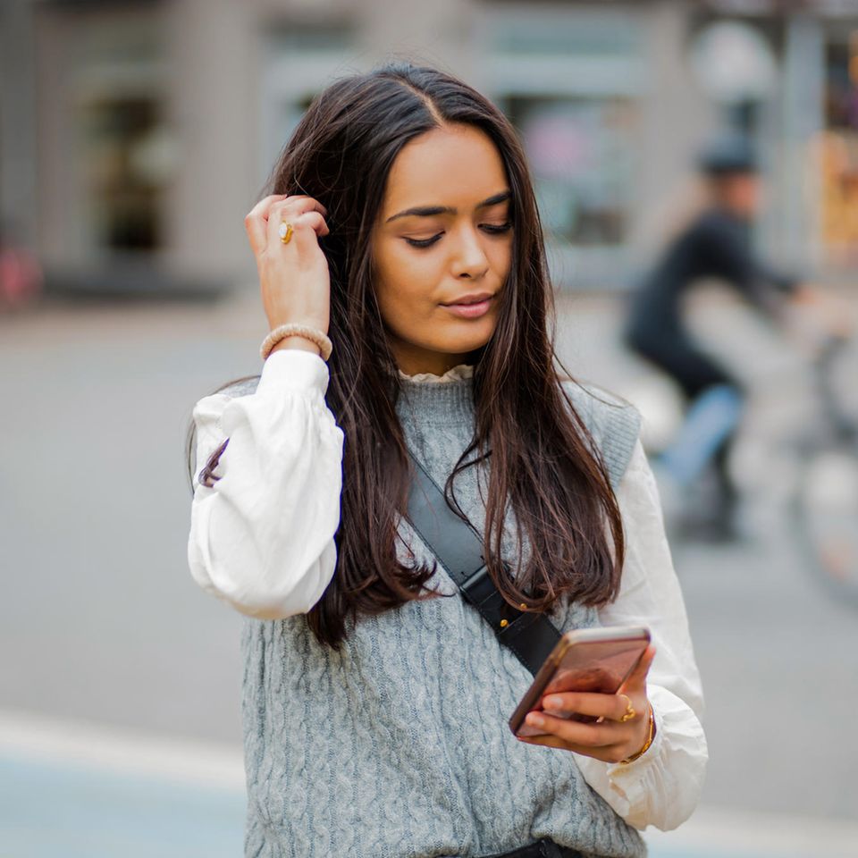 Frau schaut nachdenklich auf ihr Smartphone: Diese 7 Eigenschaften haben schwierige Personen