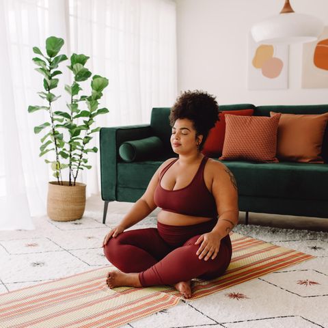 Frau meditiert im Wohnzimmer | Selfcare-Horoskop: So entspannt Ihr Sternzeichen am besten
