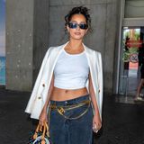 Dass sich mehrere Logos nicht unbedingt beißen müssen, beweist Lena Mahfouf. Die Autorin zeigt sich bei ihrer Ankunft an der Côte d’Azur mit weitgeschnittener Jeans, Crop-Top und Blazer. Dazu kombiniert sie einen Kettengürtel von Chanel sowie eine Louis Vuitton Alma-Bag mit buntem Monogram. Adidas Sambas machen das Outfit reisetauglich. 