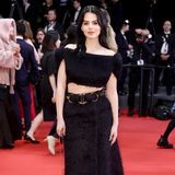 Schauspielerin Ruby O. Fee strahlt auf dem Red Carpet in Cannes und wirkt mit ihrem schwarzen Fell-Ensemble aus Rock und passendem Top wie eine mysteriöse Fee. Die kleine goldene Tasche sorgt bei ihrem Look für die Extra-Portion Glamour.