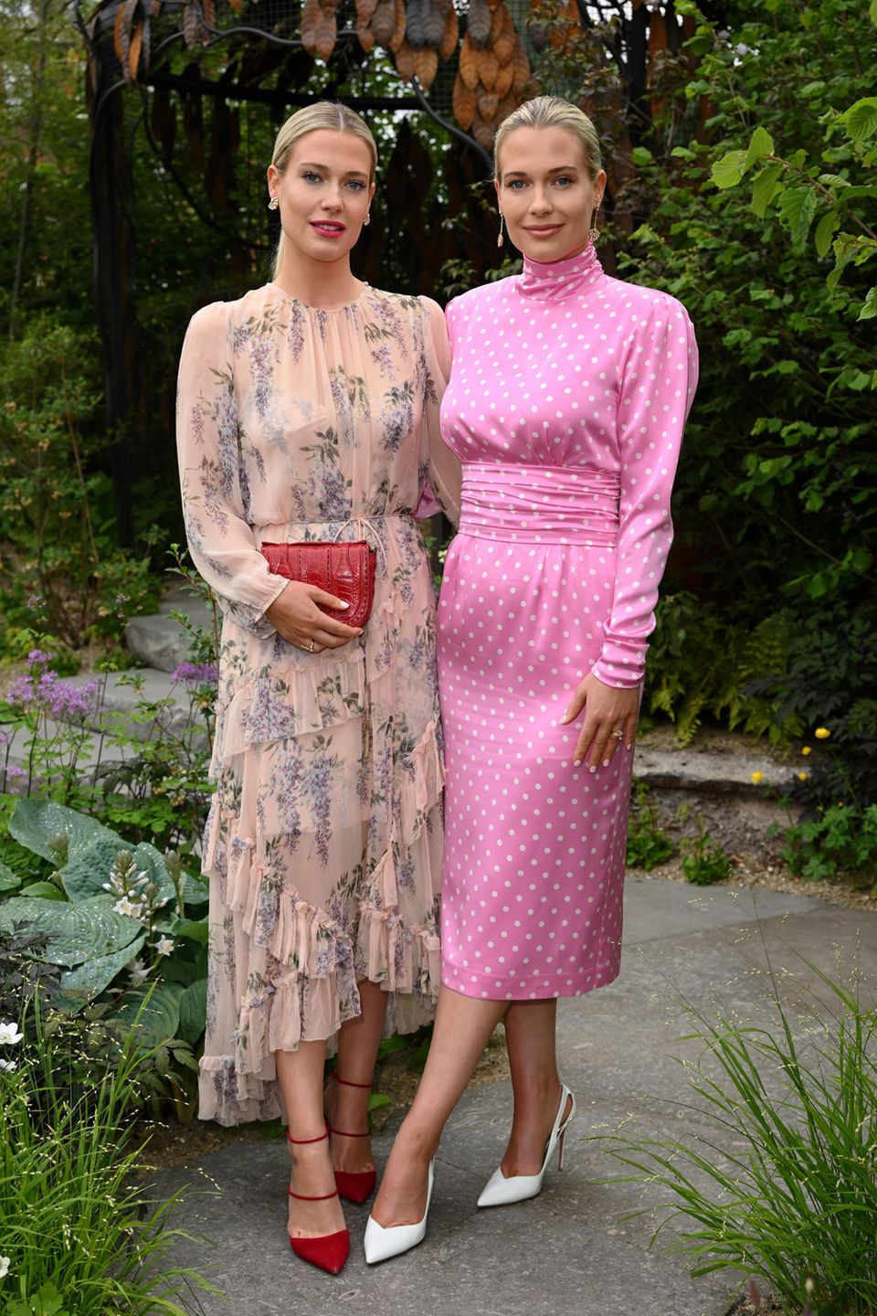 Amelia und Eliza Spencer begeistern bei der Chelsea Flower Show in frühlingshaften Looks. Während Amelia für den Anlass auf ein langes Blumenkleid von Zimmermann zurückgreift und mit roten Accessoires Akzente setzt, wählt ihre Zwillingsschwester Eliza ein pinkfarbenes Polka-Dot-Kleid von Alessandra Rich. Ein beliebtes Design bei den Spencer-Ladys! Auch ihre Tante, Lady Diana, trug bereits ein ganz ähnliches pink-weißes Design bei ihrer Australienreise im Frühjahr 1983.