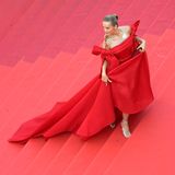 Petra Němcová verschmilzt farblich mit den roten Stufen unter ihr — schafft es dann aber doch, mit ihrer ausladenden Robe herauszustechen. Das Kleid mit langer Schleppe und Carmen-Ausschnitt, welcher links und rechts in zwei Schleifen mündet, wird durch ein XXL-Collier mit vier Bahnen zum doppelten Hingucker.