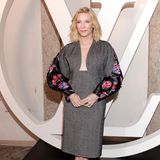 Auch Cate Blanchett ist anlässlich der Modenschau nach Italien gereist, posiert in einem Tweedkleid mit auffälligem Ausschnitt und Ballonärmeln für die Fotograf:innen. Schlichte Sandaletten runden den Look ab. 
