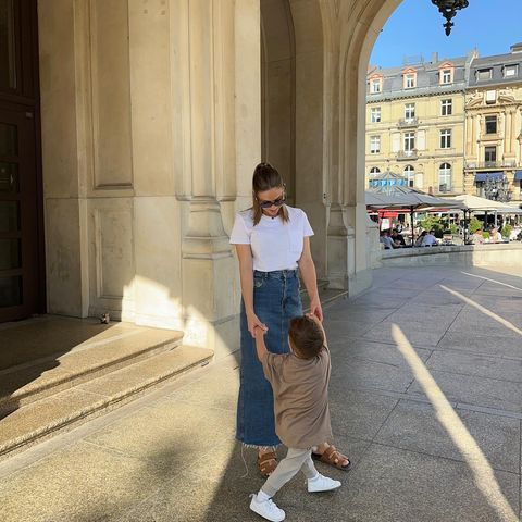 Ann-Kathrin Götze ist mit ihrem Sohn Rome unterwegs und trägt dabei DEN Sommertrend des Jahres: einen Maxi-Jeansrock. Ein weißes Basic-Shirt und Sandalen von Hèrmes vervollständigen den City-Look. 