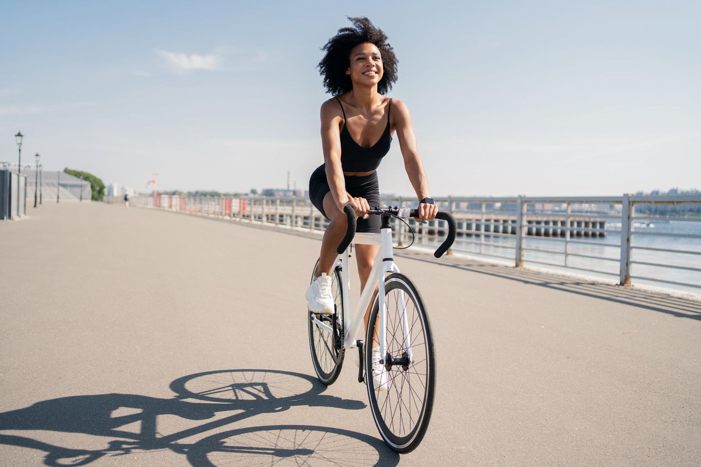 Frau fährt Fahrrad am Meer: Diese 3 Sommer-Workouts verbrennen die meisten Kalorien