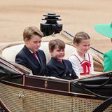 George, Louis und Charlotte begeistern nicht nur mit ihren Gesichtsausdrücken, sondern auch in formellen Looks. Charlotte trägt ein weißes Kleid mit roten Details wie Linien und Schleife und hat ihr Haar im tiefen Dutt mit geflochtenen Details zurückgebunden. Ihre Brüder begeistern in dazu passenden Looks: Navyblaue Anzüge treffen auch hier auf Rot in Form ihrer Krawatten. 