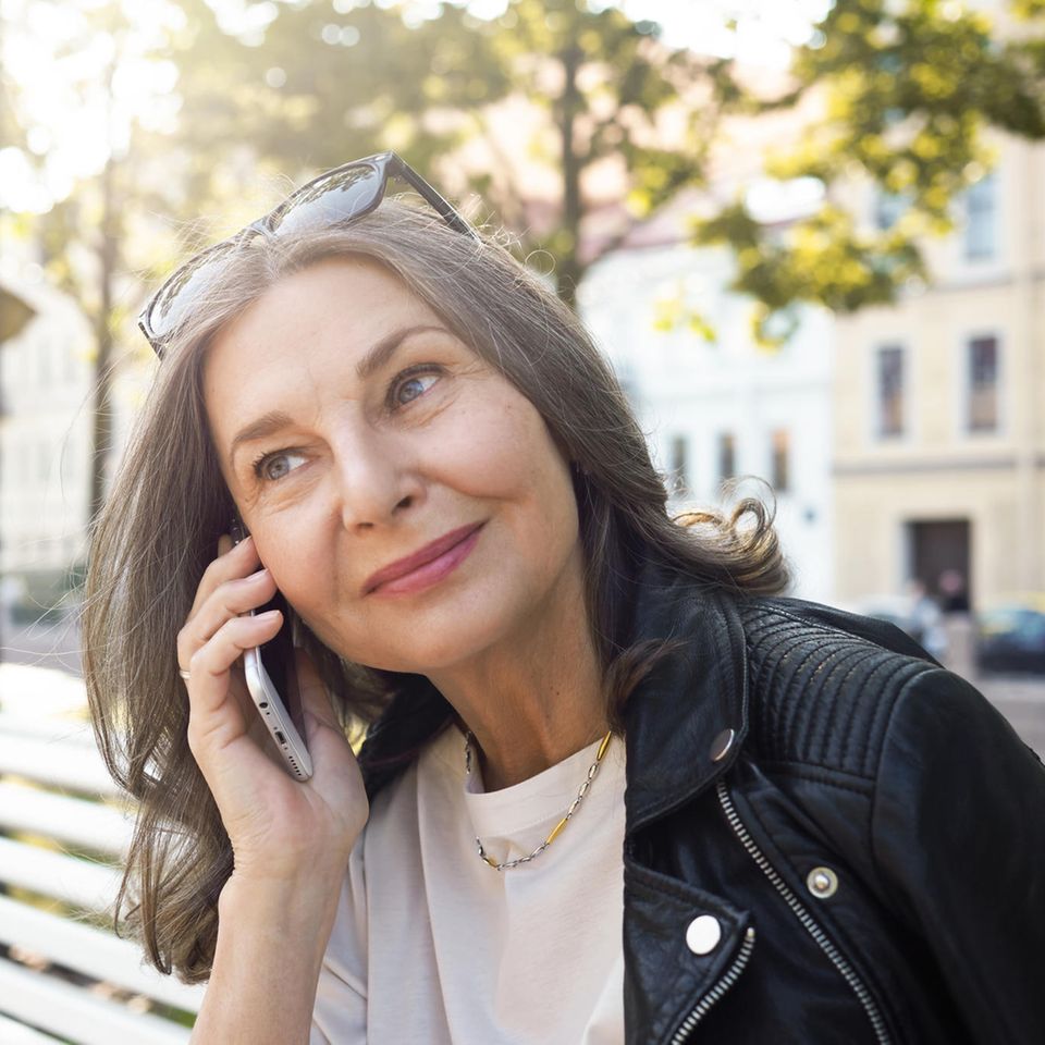 Frau telefoniert auf einer Bank: 4 Tipps, wie Sie am besten mit launischen Menschen umgehen