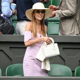 Jelena Djokovic setzt als Zuschauerin auf ein fein gestreiftes Bandeau-Kleid in Rosa und Weiß und eine weiße Lady Dior. Ein Hut mit breiter Krempe sorgt für einen glamourösen Auftritt beim Sport-Event. 