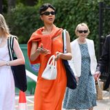Auch "Queen Charlotte"-Star India Amarteifio springt auf den Styling-Zug mit auf, trägt ihren Zopfstrickpullover in Orange lässig über den Schultern geknotet. Dazu stylt sie ein Satin-Slip-on-Dress – ebenfalls in Orange.