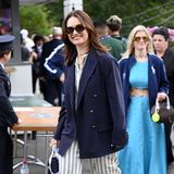 Schauspielerin Lily James lächelt voller Vorfreude in die Kameras der Fotograf:innen. Ihr Outfit des Tages: Ein gestreifter Zweiteiler, über den sie einen Oversized-Blazer in Dunkelblau kombiniert. 