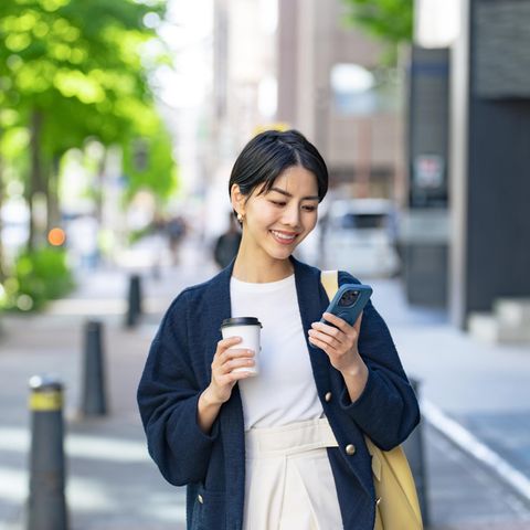 Fröhliche Frau mit Handy und Kaffee: Diese 5 Gedanken haben psychische gesunde Menschen täglich