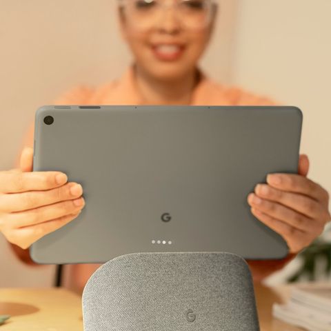 Eine Nutzerin nimmt das Google Pixel Tablet von seinem Ladedock.