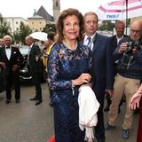 Salzburg kann sich über königlichen Besuch aus Schweden freuen: Silvia und, im Hintergrund, ihr Mann König Carl Gustaf besuchen während der Opernfestspiele die Premiere von "Orfeo ed Euridice" im Großen Festspielhaus. Richtig festlich glänzt dabei auch ihr floraler Glamour-Look in Dunkelblau.