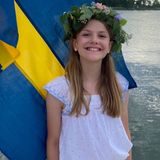 Posieren wie die Großen! Prinzessin Estelle lächelt mit einem Blumenkranz auf dem Kopf vor der schwedischen Flagge in die Kamera. 