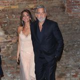 Amal Clooney und George Clooney machen vor dem Start der Filmfestspiele Venedig unsicher. Während es vorher nur zu privaten Dates ging, zeigt sich das Paar elegant zum ersten offiziellen Termin. Amal wählt dafür ein cremefarbenes Slip-On-Dress aus Spitze und Tüll und sorgt damit für Wedding-Vibes. 