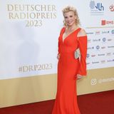 Eva Habermann strahlt auf dem roten Teppich des Deutschen Radiopreises in Hamburg mit ihrem roten Kleid um die Wette! Die lange Robe besticht vor allem durch ihre Schulter-Cut-Outs, auch mit ihrem Beauty-Look ist die Schauspielerin eine Erscheinung: Kleine Engelslocken treffen hier auf zartes Gloss und goldenen Lidschatten.    