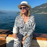Mit Hut und Sonnenbrille, einem Glas Wein in der Hand und vor der Traumkulisse des Comer Sees lässt sich Veronica Ferres ablichten. Für eine Hochzeit von Freunden hat sich die Schauspielerin für ein blau-weißes Maxikleid mit floralem Muster und langen Ärmeln entschieden. 