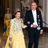 Königin Sonja von Norwegen läuft an der Seite von Guðni Thorlacius Jóhannesson, dem Präsident von Island, in den Saal. Sie setzt, ebenso wie die schwedische Königin, auf eine Robe in Gelb.