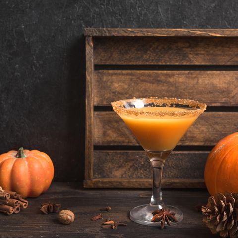 Pumpkin Spice Martini neben Kürbissen und Tannenzapfen