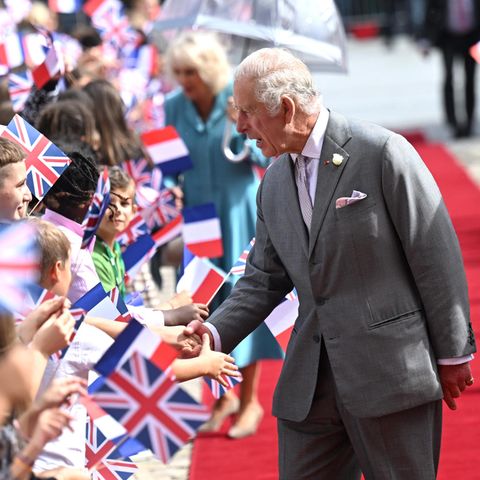 Auch König Charles begrüßt die wartenden Zaungäste am roten Teppich. 