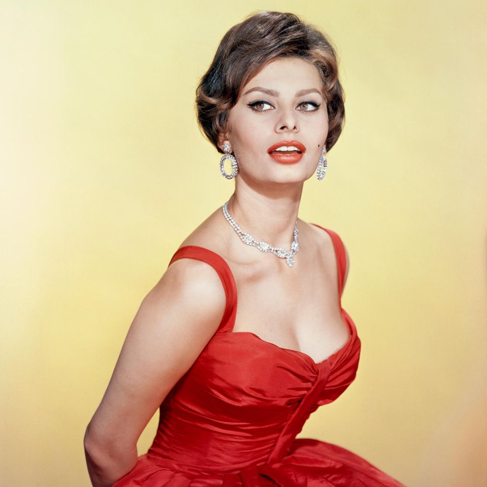 1955  Sophia Loren inszeniert sich gern vor der Kamera. Hier posiert sie für ein glamouröses Porträt mit Diamanten und in einem roten Kleid. 