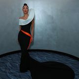 Auf der Press Night Afterparty von "Sunset Boulevard" in London präsentiert Nicole Scherzinger einen extravaganten Look. Ihr schwarz-weißes asymmetrisches Kleid mit langer Schleppe macht sie zum Star des Abends. Ein dünnes orangefarbenes Band ziert ihre Taille wie ein improvisierter Gürtel und verleiht ihrem Look einen aufregenden Farbstich.
