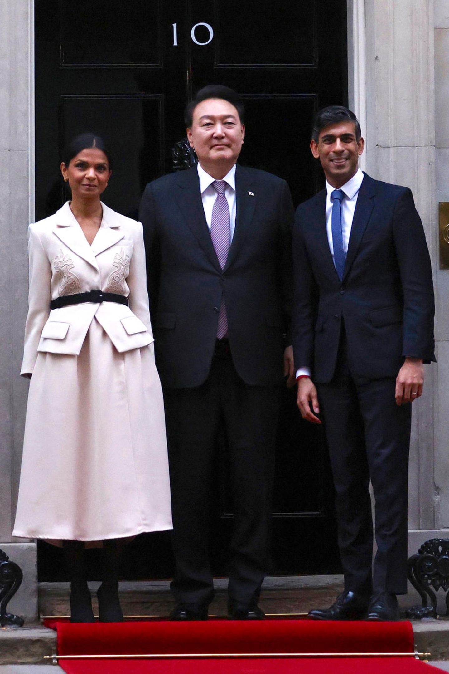 Um den südkoreanischen Präsidenten Yoon Suk Yeol zu begrüßen, erscheint der britische Premierminister Rishi Sunak mit seiner Ehefrau Akshata Murty. Dabei setzt die indische Geschäftsfrau auf ein Midi-Kleid der Londoner Marke Self-Portrait für rund 480 Euro. Die aus schwerem Krepp gefertigte Kreation mit schmal geschnittener Silhouette und Schulterpolstern wirkt auf den ersten Blick wie eine Blazer-Rock-Kombination. Ein schwarzer Gürtel betont Akshatas Taille, farblich dazu stimmt sie ihre blickdichte Strumpfhose und Pumps ab. Ein gelungener Look für die Milliardärstochter – mit ihrem guten Modegeschmack ist sie nicht alleine. Eineinhalb Jahre zuvor konnte sich diese royale Dame ebenfalls für das Midi-Kleid begeistern.