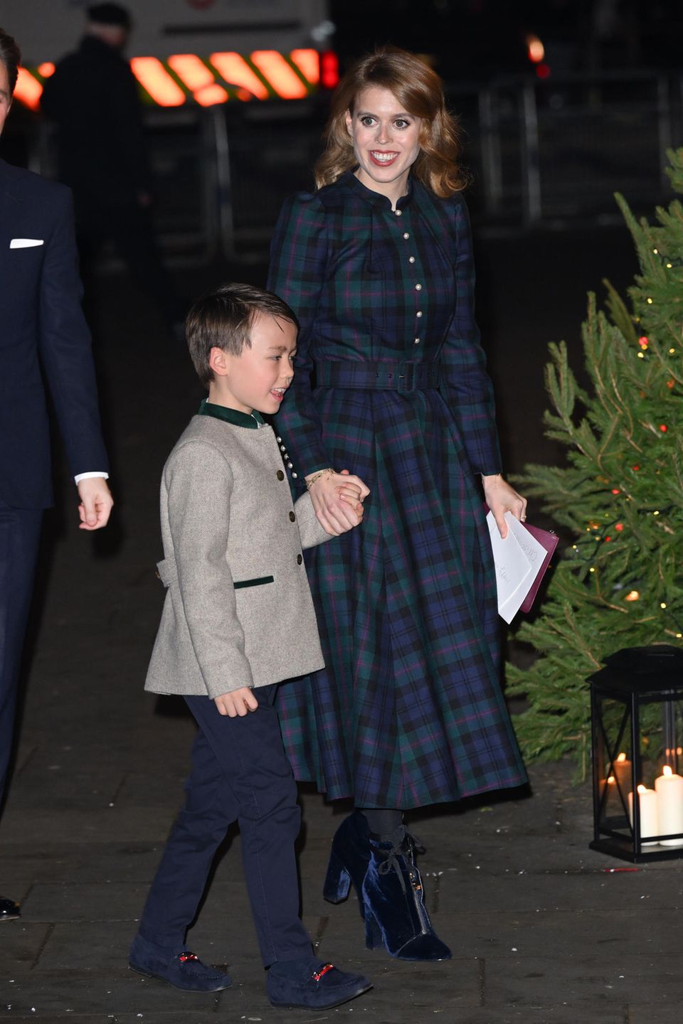 Hand in Hand mit ihrem Stiefsohn Wolfie zeigte sich Prinzessin Beatrice beim Weihnachtskonzert "Together at Christmas" in der Londoner Westminster Abbey. Für den festlichen Anlass entscheidet sich Beatrice für ein hochgeschlossenes Kleid mit Karomuster von Beulah London. Ein besonderes Highlight ihres Looks sind die dunkelblauen Samtboots von Zara, die direkt für festliche Stimmung sorgen.