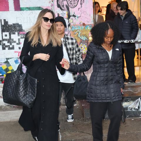 Zusammen mit ihren Kindern verlässt Angelina Jolie das ehemalige Studio des amerikanischen Künstlers Jean-Michel Basquiat. Gewohnt schlicht kleidet sich die Schauspielerin ganz in Schwarz, ihr langer Mantel mit Knopfleiste ist trotzdem ein Hingucker. Ebenso wie ihr Maxi-Shopper, bei dem es sich wohl um den Yves Saint Laurent Icare handelt. Leder-Stiefeletten mit Absatz und eine große Sonnenbrille machen den Alltags-Look von Angelina komplett. Tochter Zahara Marley Jolie lässt es modisch ebenso ruhig angehen – so bietet die Familie ein Kontrastprogramm zu all den glamourösen Weihnachts-Looks.