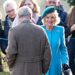 Fröhlich lächelt Königin Camilla ihren Gatten König Charles an.