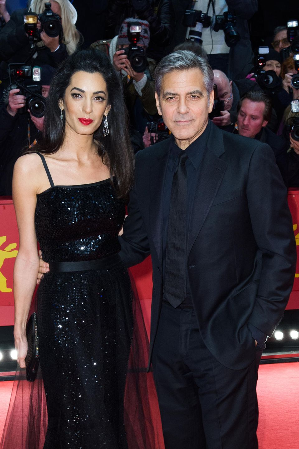 Amal Clooney ist und bleibt eine klassische Schönheit – Make-up unterstreicht diese nur. Und zwar genau so: Ihre vollen dunklen Haare hat die Anwältin zum Half-Updo gestylt, rote Lippen und ein mitternachtsschwarzer Lidstrich sorgen für nobles Drama auf dem roten Teppich in Berlin.