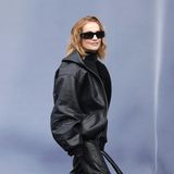 Ganz lässig zeigt sich Isabelle Huppert mit Sonnenbrille und Leder-Bomberjacke auf dem Weg zur Show von Balenciaga.