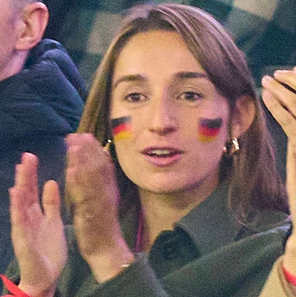 Lena Wurzenberger mit Deutschlandfahne im Gesicht und dem pinken Trikot unter ihrer Jacke beim Spiel gegen die Niederlande.